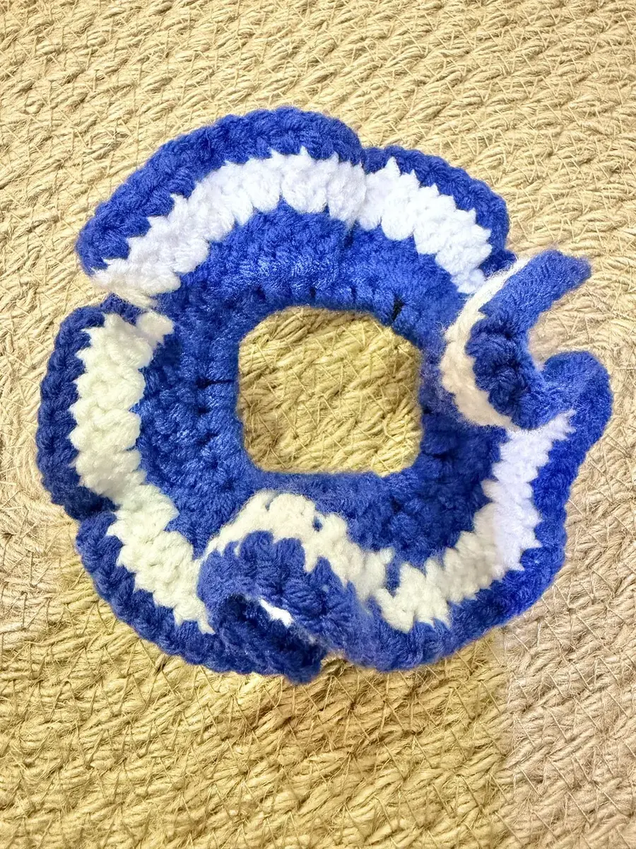 A handmade ruffle scrunchie in royal blue with cream stripes.