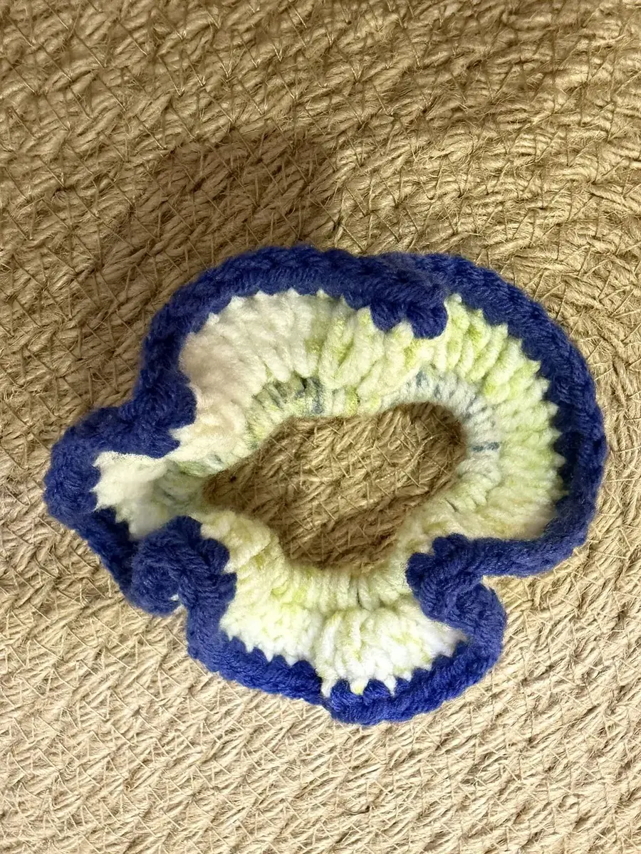 A handmade ruffle scrunchie in pale yellow-green with a navy edge.