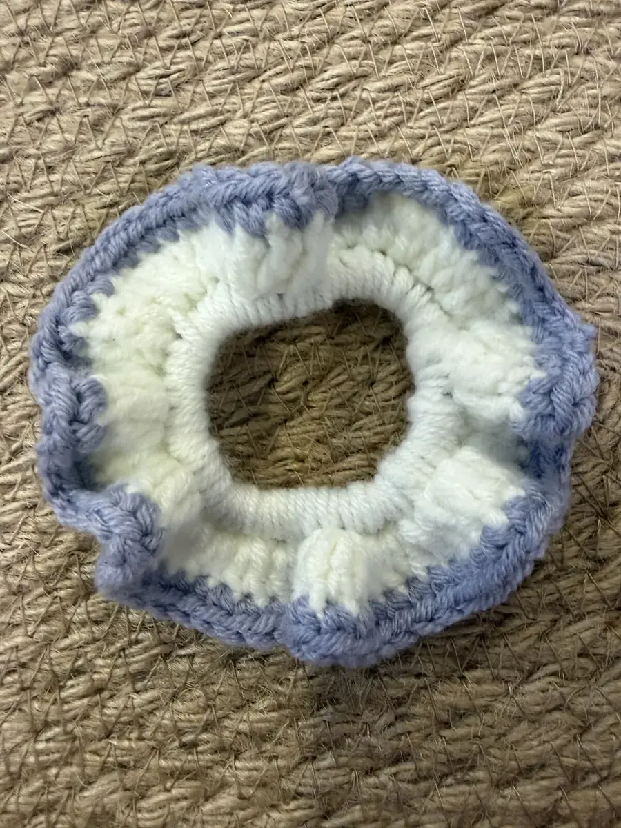 A handmade ruffle scrunchie in cream with a blue-grey edge.