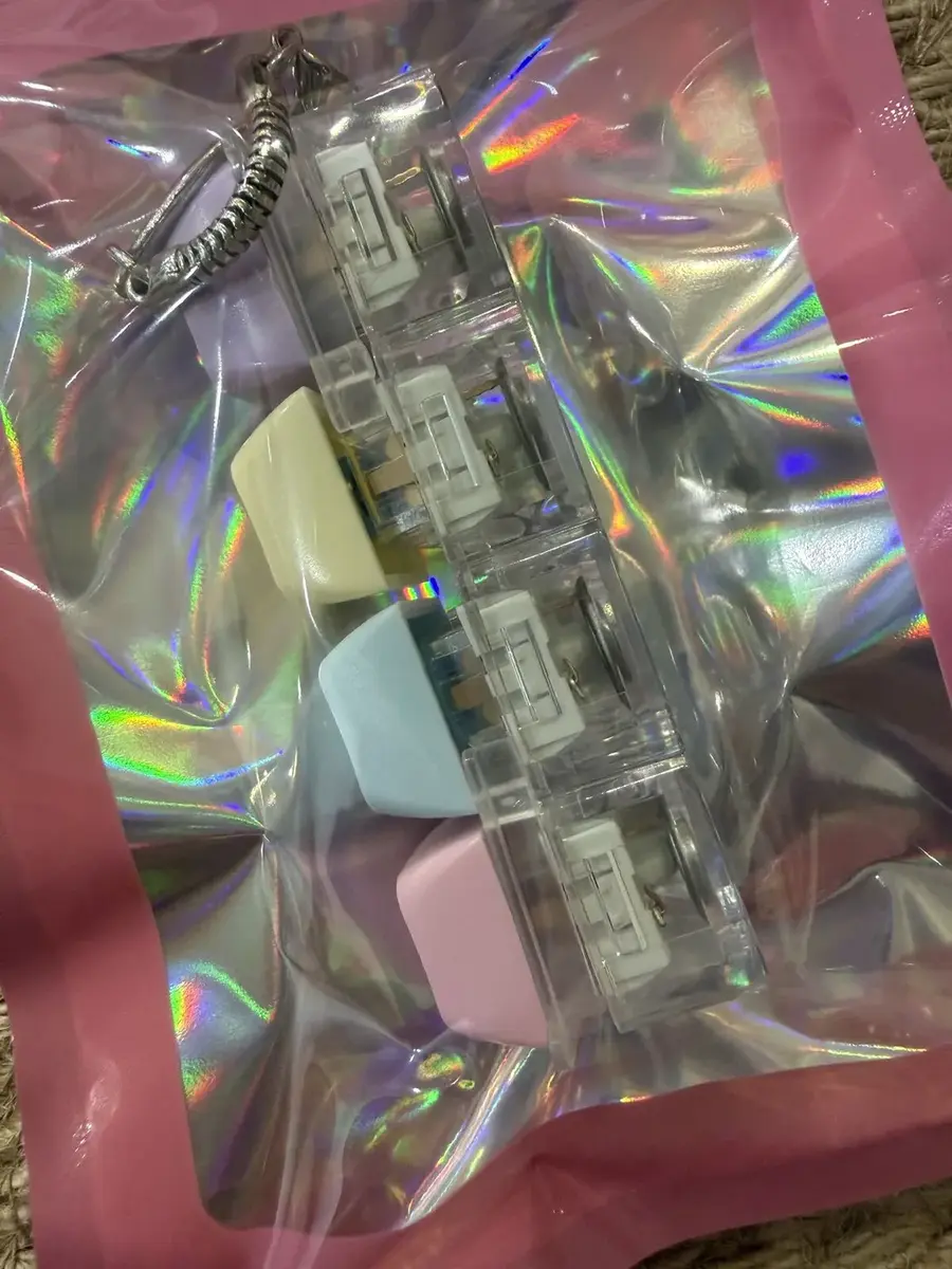 Pastel keycap clickers in a holographic bag.