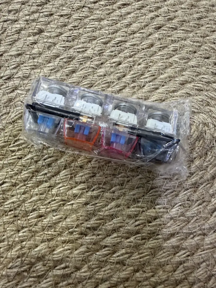 A strip of four dark keycap clickers.