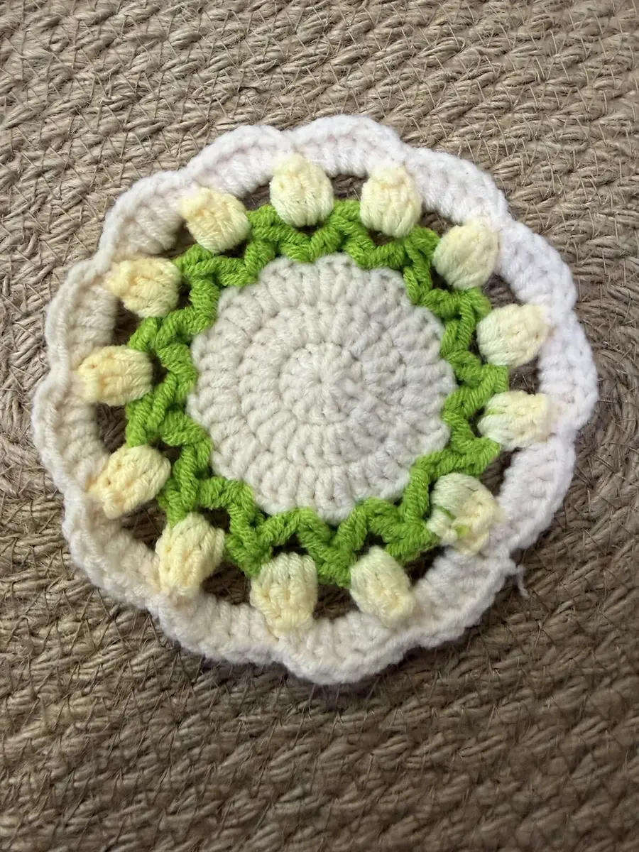 A flower coaster with pale yellow puffs.