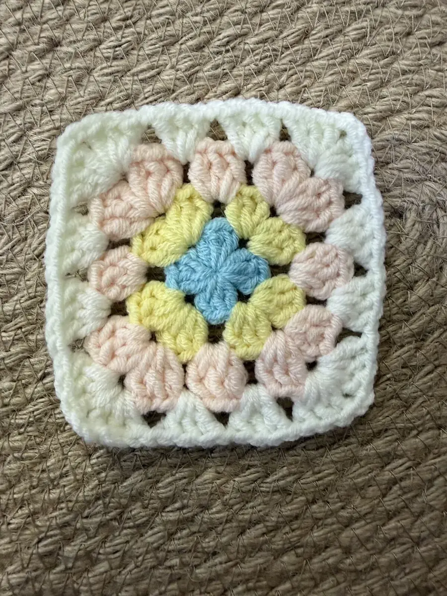 A pastel granny square in pink, yellow, green and blue.